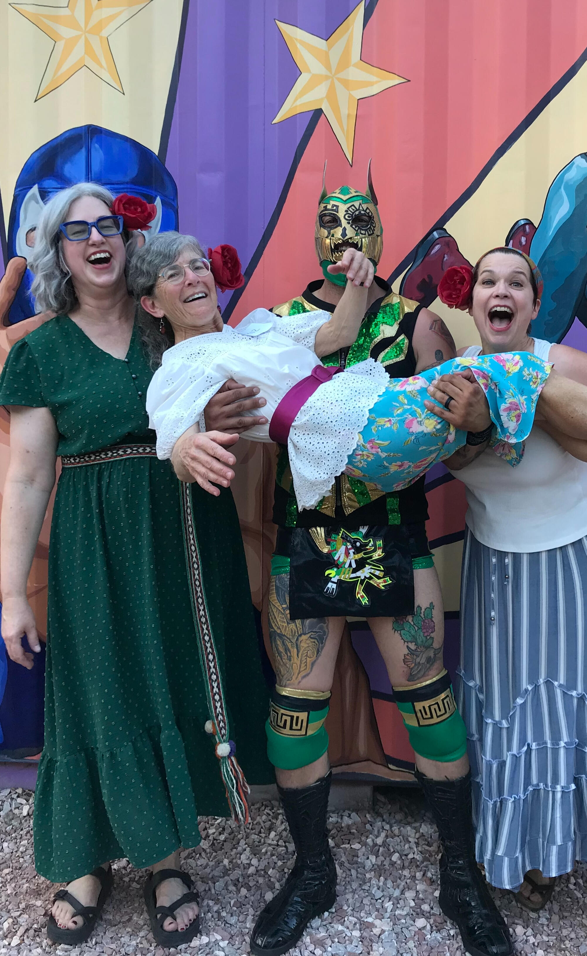 Three smiling women posing with a Luchal Libre wrestler